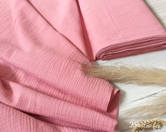 Könnte beinhalten: Eine Rolle weichen, rosa Stoffes mit einer strukturierten, gekreppten Oberfläche. Der Stoff ist gefaltet und drapiert, ein Teil ist aufgerollt. Das Bild zeigt auch getrocknete Weizenstiele und den Text "Kreativ-fee".