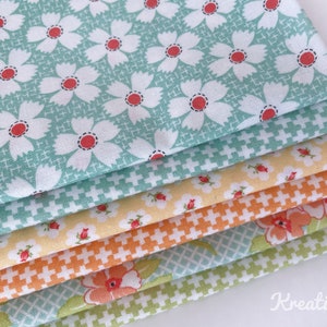 K&ouml;nnte beinhalten: Ein Stapel bunter Stoffmuster mit floralen und geometrischen Mustern. Der oberste Stoff ist hellt&uuml;rkis mit wei&szlig;en G&auml;nsebl&uuml;mchen und roten Zentren. Weitere Stoffe sind gelb, orange und gr&uuml;n mit verschiedenen Blumen- und Kreuzstichmustern.