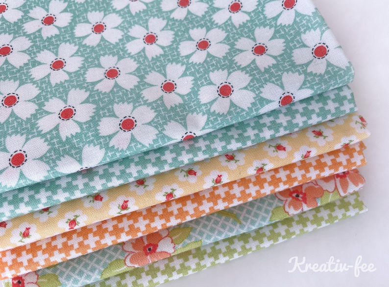 K&ouml;nnte beinhalten: Ein Stapel bunter Stoffmuster mit floralen und geometrischen Mustern. Der oberste Stoff ist hellt&uuml;rkis mit wei&szlig;en G&auml;nsebl&uuml;mchen und roten Zentren. Weitere Stoffe sind gelb, orange und gr&uuml;n mit verschiedenen Blumen- und Kreuzstichmustern.