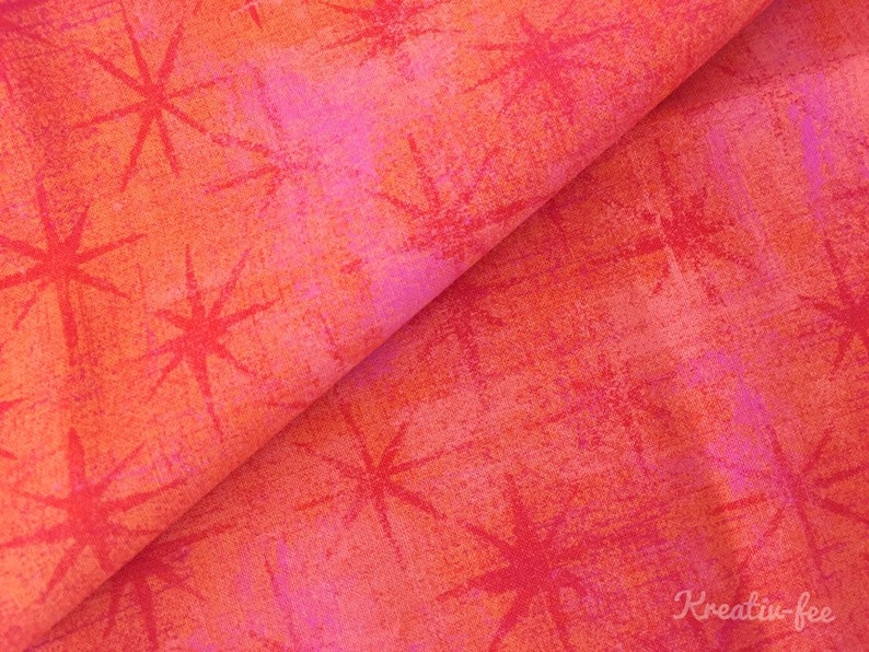 Peut inclure: Tissu pli&eacute; avec un motif abstrait vibrant. Le tissu pr&eacute;sente un m&eacute;lange de teintes orange, rouge et rose, avec un aspect textur&eacute;. Des motifs d'&eacute;clats d'&eacute;toiles rouges sont dispers&eacute;s sur la surface, cr&eacute;ant un effet visuel dynamique. Le tissu convient &agrave; divers projets d'artisanat.