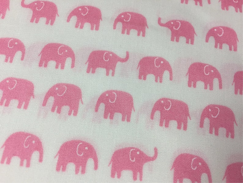 Puede incluir: Tela blanca con un patr&oacute;n repetitivo de elefantes rosas. Cada elefante est&aacute; representado en un estilo simple de dibujos animados, con una trompa curva y orejas grandes. Los elefantes est&aacute;n espaciados uniformemente en la tela.