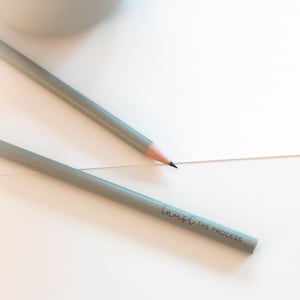 Könnte beinhalten: Zwei graue Bleistifte auf einer weißen Oberfläche. Ein Bleistift trägt den Text "Trust the Process".