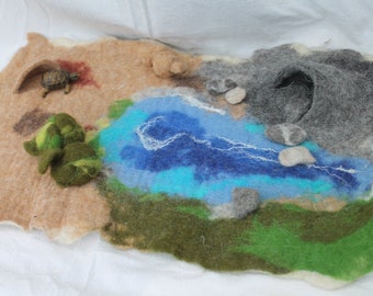 Paysage de savane en feutre, un tapis de jeu en feutre avec grotte de sable, trou d'eau, rivière, grande grotte de pierre. 5 pierres, trois buissons.