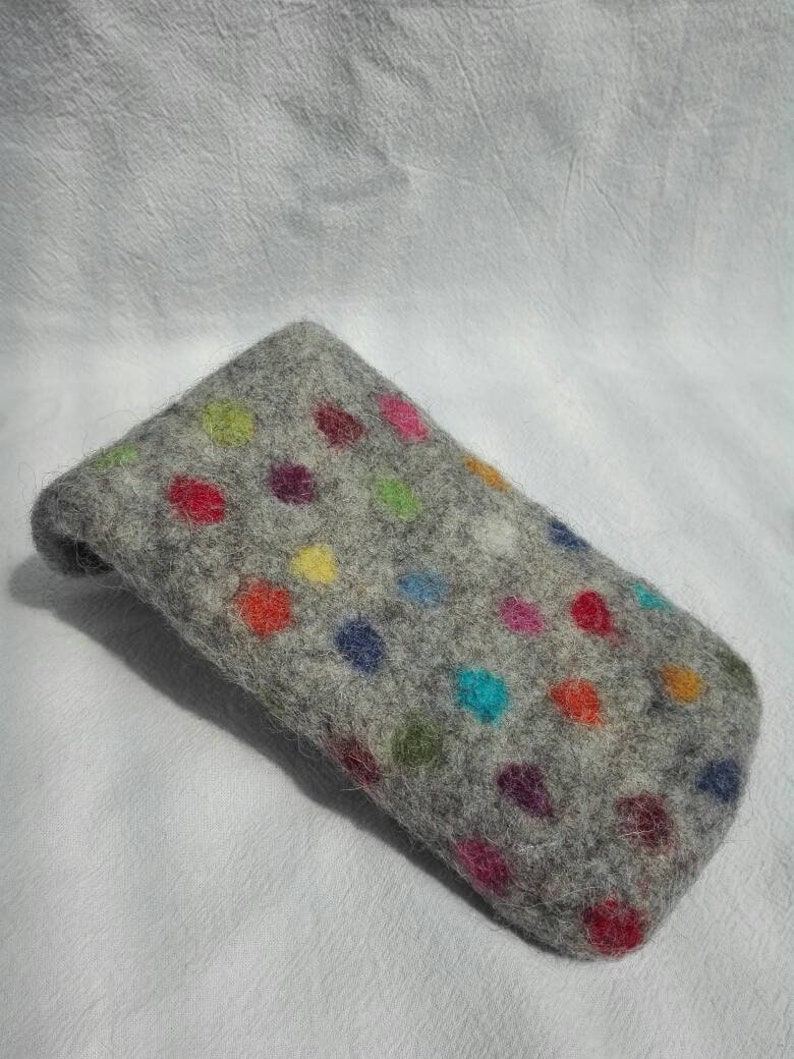 May include: A gray felt phone case with a colorful polka dot pattern. The dots are in various shades of red, blue, green, yellow, and pink.