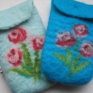 Puede incluir: Dos fundas de teléfono de fieltro con diseños florales. Una funda es azul claro con flores rosas y rojas. La otra funda es azul turquesa con flores rojas y blancas.