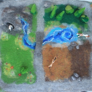 Könnte beinhalten: Eine Filzspielmatte mit einer grünen und braunen Landschaft, einem blauen Fluss und grauen Steinen. Auf der Matte befinden sich kleine Spielzeugtiere, darunter ein weißes Schaf und ein braunes Pferd.