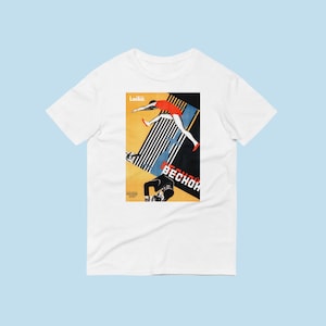 Puede incluir: Camiseta blanca con un estampado gráfico de un cartel de propaganda soviética vintage que representa a una mujer saltando sobre una barra con el texto "Lekko!" y "BECHOK!" en cirílico.