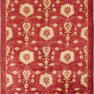 Puede incluir: Una alfombra roja con un diseño persa tradicional que presenta intrincados patrones florales en color crema. La alfombra tiene un brillo sutil y una textura suave.