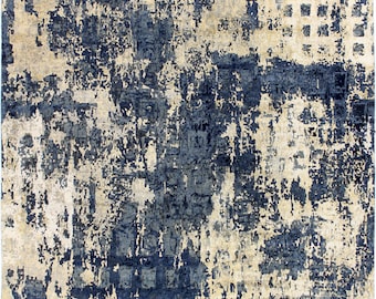Puede incluir: Alfombra de área abstracta con un aspecto desgastado y descolorido. La alfombra presenta una mezcla de tonos beige y azul en un patrón moteado.