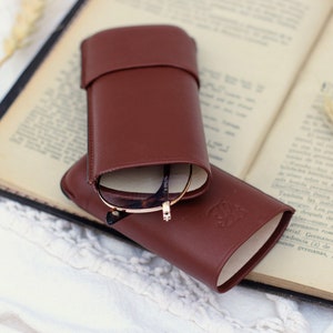 open brown leather glasses case with your glasses inside on an old open book