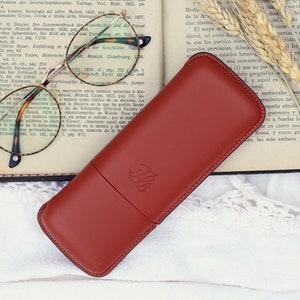 orange-brown leather glasses case with talabar logo engraved on an old open book