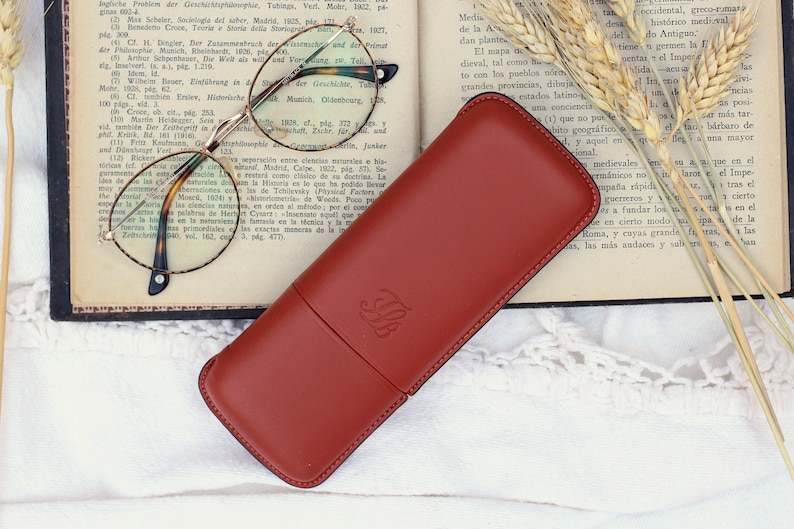 orange-brown leather glasses case with talabar logo engraved on an old open book
