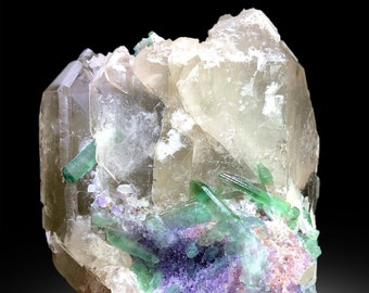 May include: A cluster of clear quartz crystals with green and purple inclusions. The quartz crystals are translucent and have a glassy luster. The green inclusions are elongated and have a striated surface. The purple inclusions are smaller and more rounded.