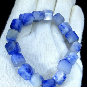 May include: A blue and white gemstone bracelet with faceted beads. The bracelet is made of natural stones and has a unique, marbled pattern.