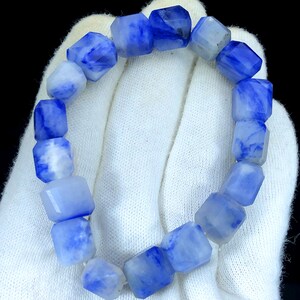 May include: A blue and white gemstone bracelet with faceted beads. The bracelet is made of natural stones and has a unique, marbled pattern.