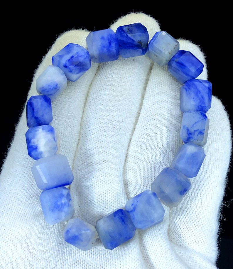 May include: A blue and white gemstone bracelet with faceted beads. The bracelet is made of natural stones and has a unique, marbled pattern.