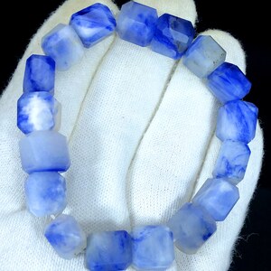 May include: A blue and white gemstone bracelet with faceted beads. The bracelet is made of natural stone and has a unique, marbled pattern.