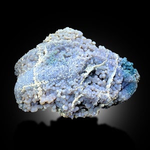 May include: A large, irregularly shaped, purple and blue agate with a textured surface. The agate is covered in small, round nodules.