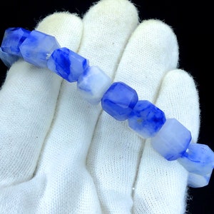May include: A bracelet made of blue and white agate beads. The beads are faceted and have a unique, marbled pattern.