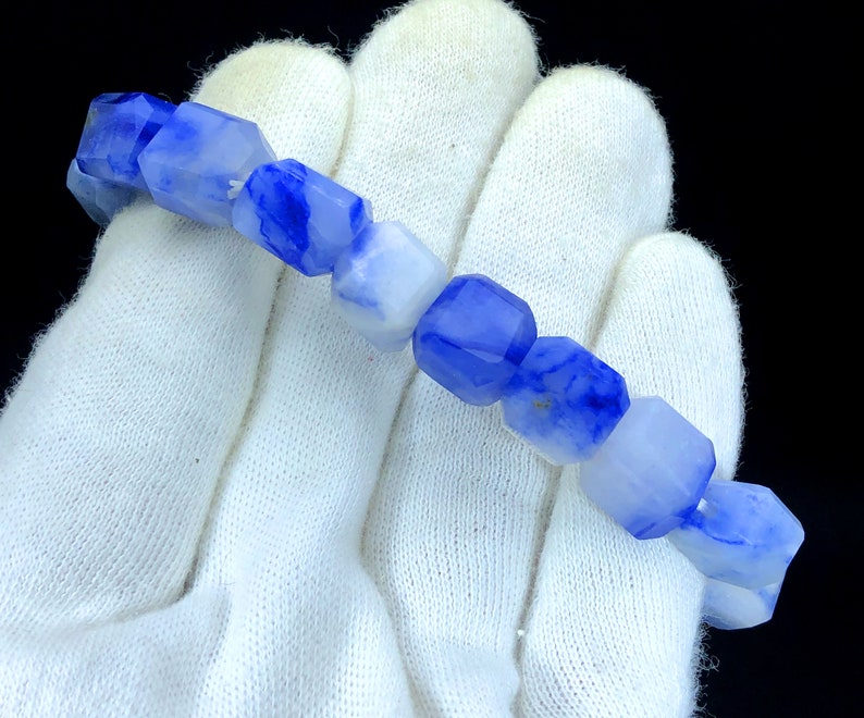 May include: A bracelet made of blue and white agate beads. The beads are faceted and have a unique, marbled pattern.