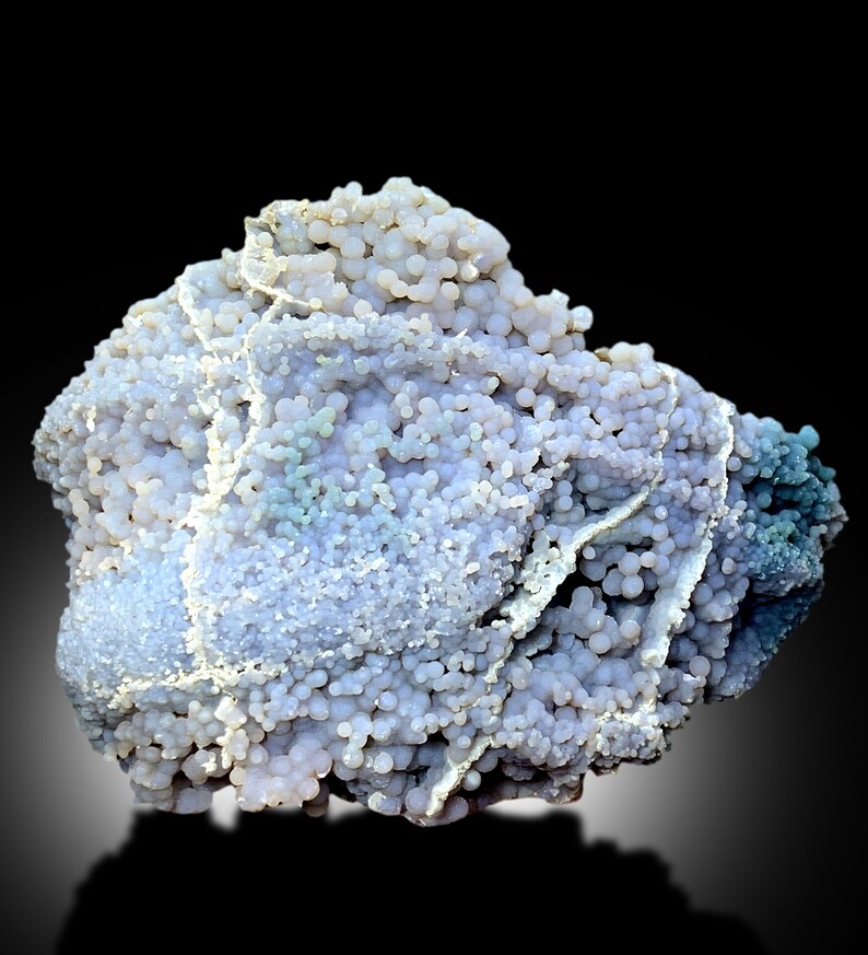 May include: A large, irregularly shaped, light purple and blue agate with a botryoidal texture. The agate has a smooth, polished surface and is covered in small, round nodules.