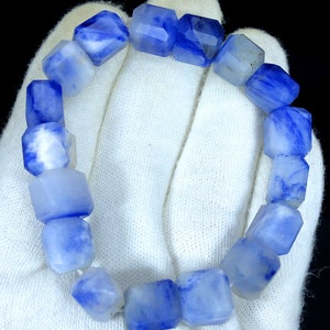 May include: A blue and white gemstone bracelet with faceted beads. The bracelet is made of natural stones and has a unique, swirling pattern.