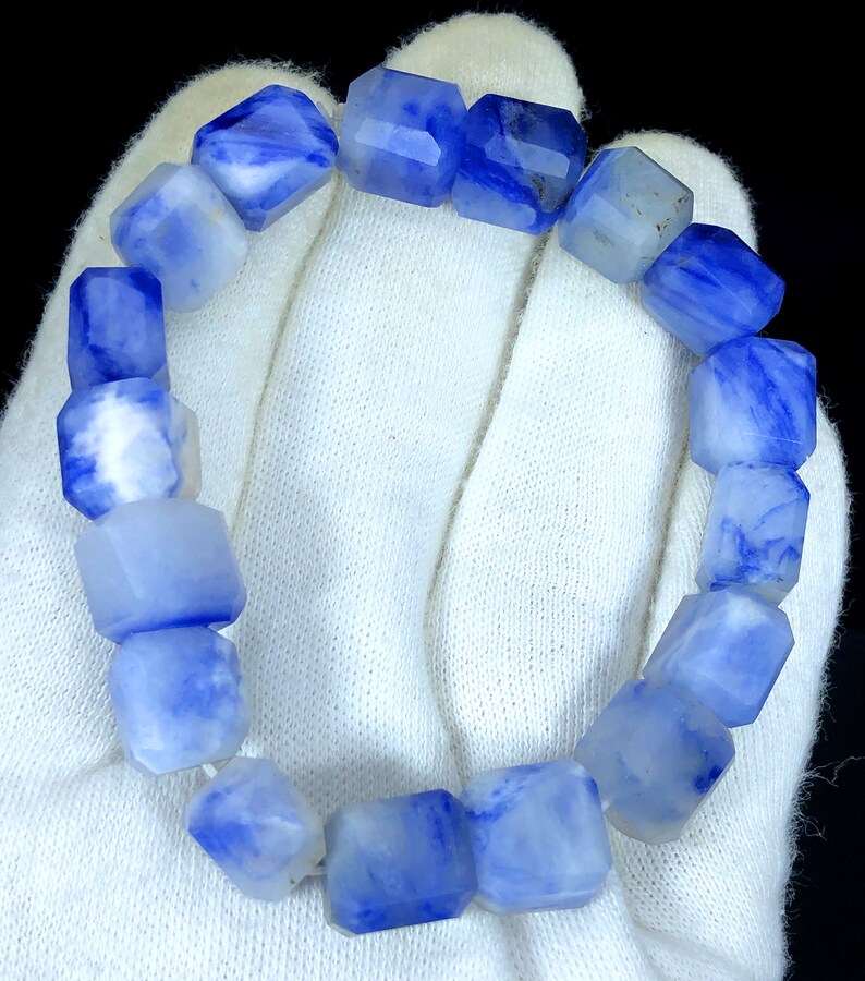 May include: A blue and white gemstone bracelet with faceted beads. The bracelet is made of natural stones and has a unique, swirling pattern.
