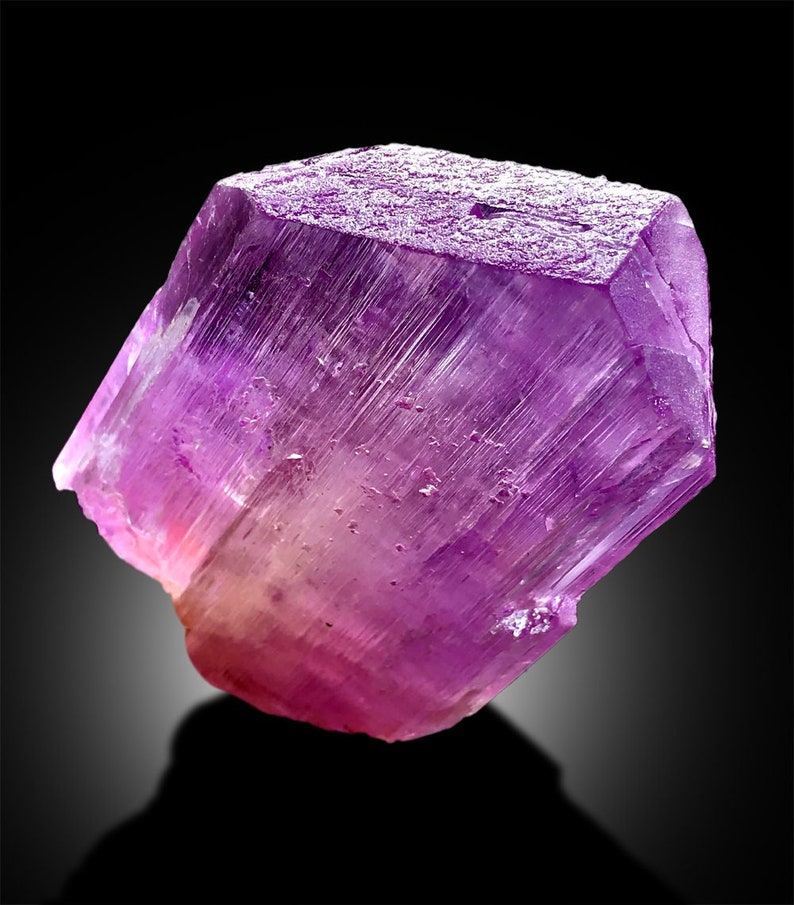 Puede incluir: Un gran cristal p&uacute;rpura transl&uacute;cido con estr&iacute;as. El cristal est&aacute; facetado y tiene un ligero tono rosado.