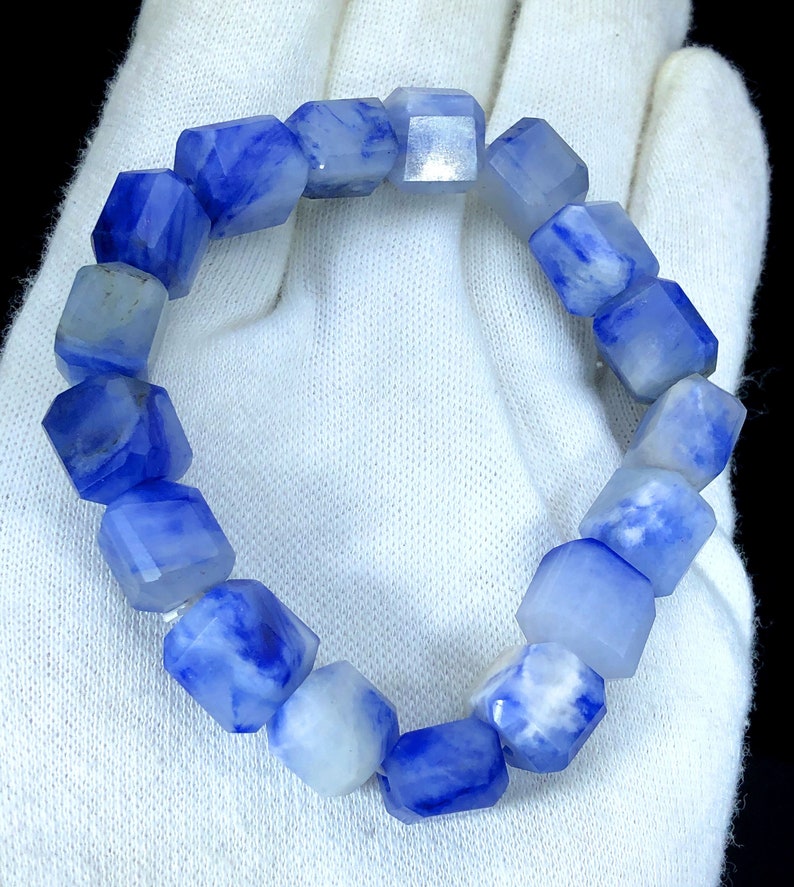 May include: A blue and white gemstone bracelet with faceted beads. The bracelet is made of natural stones and has a unique, marbled pattern.