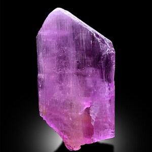 Puede incluir: Un gran cristal p&uacute;rpura transl&uacute;cido con estr&iacute;as. El cristal es facetado y tiene una punta afilada.