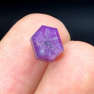 以下が含まれることがあります： 六角形の形状で、内部に星形の模様がある紫色の宝石。宝石はカットされ、研磨されています。