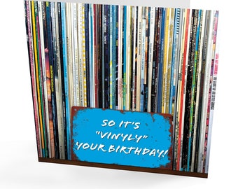 Può includere: Un biglietto di auguri per il compleanno con un cartello blu e bianco che dice "So it's "Vinyly" your birthday!" Il cartello è davanti a un muro di dischi in vinile vintage.
