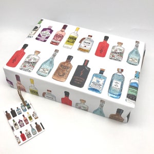 Pu&ograve; includere: Carta da regalo bianca con un motivo ripetuto di bottiglie di gin illustrate a colori. Le bottiglie hanno diverse etichette con nomi come "Greenbridge", "Loch Ness" e "Tickin".