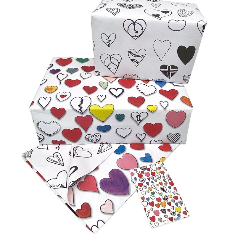 May include: Three white gift wrapping papers with a pattern of colorful hearts. The hearts are drawn in different styles, including some with a broken heart design. The papers are stacked on top of each other.