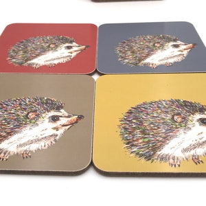 K&ouml;nnte beinhalten: Vier quadratische Untersetzer mit einer bunten Igel-Illustration auf jedem. Die Untersetzer sind in den Farben Rot, Blau, Braun und Gelb.