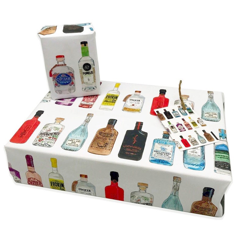 Pu&ograve; includere: Carta da regalo bianca con un motivo ripetuto di bottiglie di gin illustrate colorate. Le bottiglie hanno diverse etichette con nomi come "Fickin' Gin", "Opihr", "Loch Ness" e "Green Goblin".