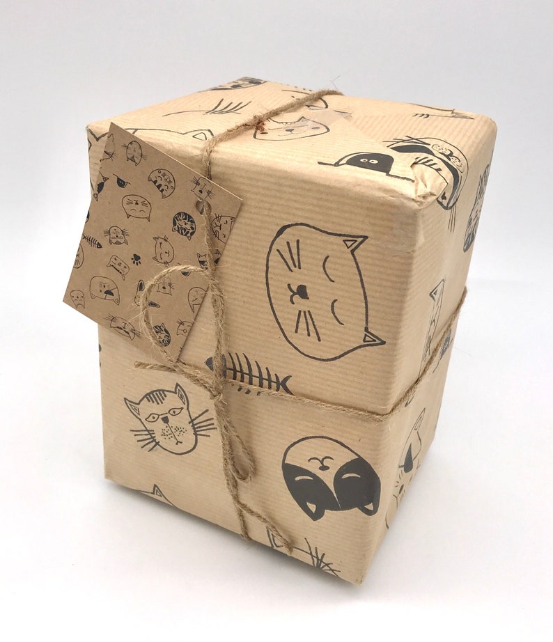 May include: A brown paper gift box with a cat-themed design. The box is wrapped with twine and has a small gift tag attached.