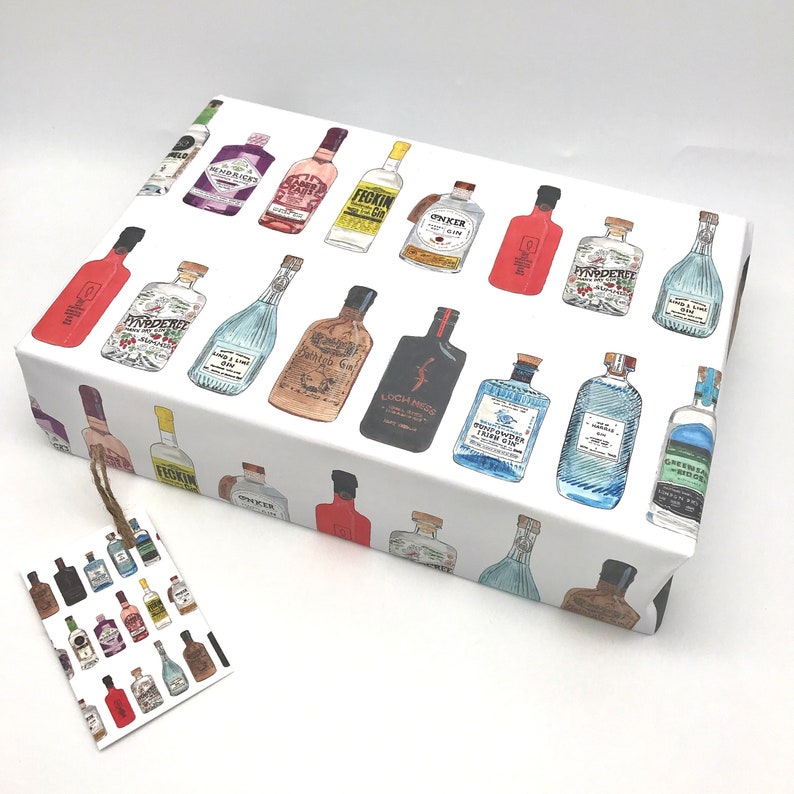 Pu&ograve; includere: Carta da regalo bianca con un motivo ripetuto di bottiglie di gin illustrate a colori. Le bottiglie hanno diverse etichette con nomi come "Greenbridge", "Loch Ness" e "Tickin".