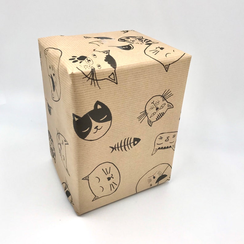 May include: Brown paper gift wrap with a repeating pattern of black cats and a fishbone. The cats have different facial expressions and are drawn in a simple, cartoon style.