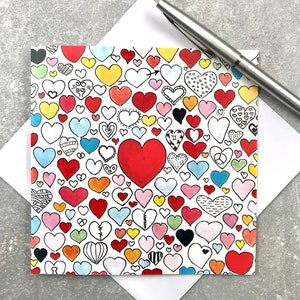 May include: A white card with a pattern of colorful hearts. The hearts are all different shapes and sizes, and some have designs on them. One large heart is red and filled in.