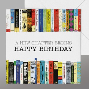 May include: A birthday card featuring a colourful illustration of a bookshelf filled with books. The text "A new chapter begins" and "Happy Birthday" is printed on the card.