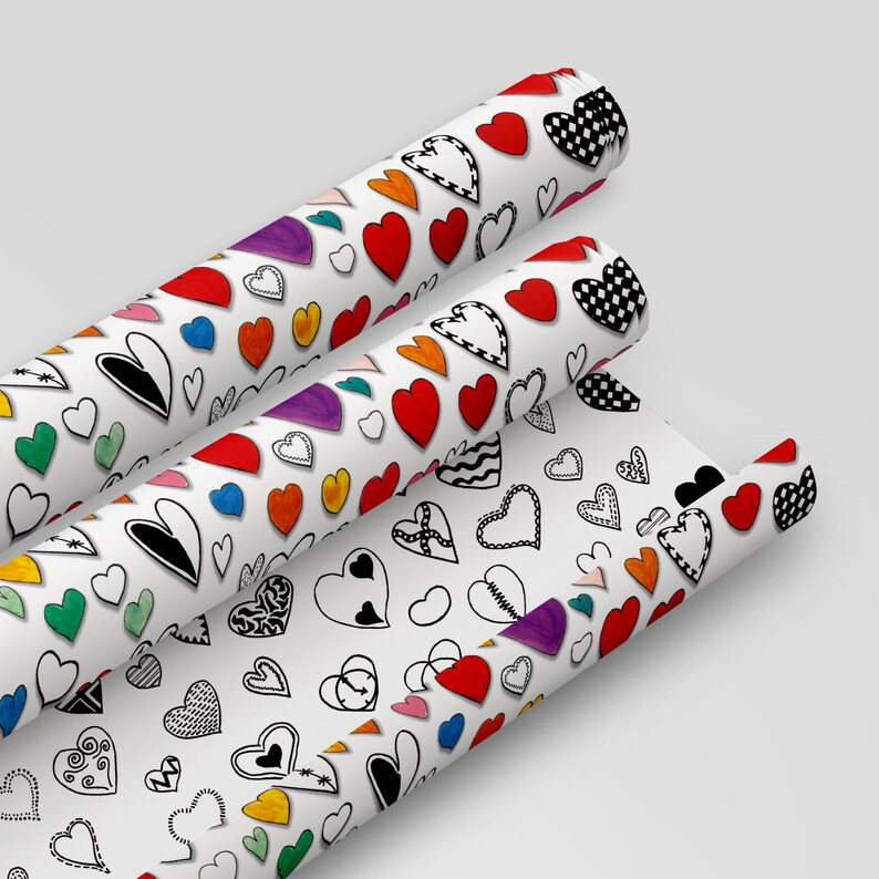 May include: Three rolls of white wrapping paper with a colorful heart pattern. The hearts are drawn in black outline and filled with various colors, including red, yellow, blue, green, and purple.