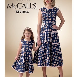 May include: A vintage McCall's sewing pattern for a dress, featuring a mother and daughter wearing matching blue and pink floral dresses. The pattern number is M7354 and the collection is called "The Archive Collection, Circa 1955".
