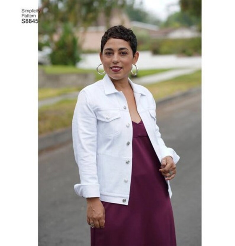 May include: A white denim jacket with a button closure and a burgundy sleeveless dress. The model is wearing silver hoop earrings.