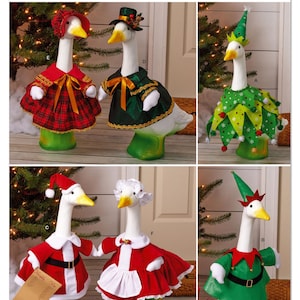 May include: Simplicity S3187 sewing pattern for goose figurines. The image displays six white goose statues wearing various holiday-themed outfits including a red plaid dress, a green cape, a green elf costume, a Santa suit, a white apron, and a red elf outfit.