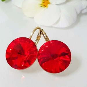 May include: A pair of red crystal earrings with gold-toned hoops. The earrings feature round, faceted crystals.