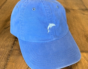 May include: A blue baseball cap with a white dolphin embroidered on the front.