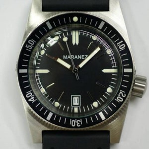 Op de afbeelding: Een zwart en zilveren polshorloge met een zwarte wijzerplaat en witte markeringen. Het horloge heeft een zwarte rubberen band en een draaibare bezel met witte markeringen.