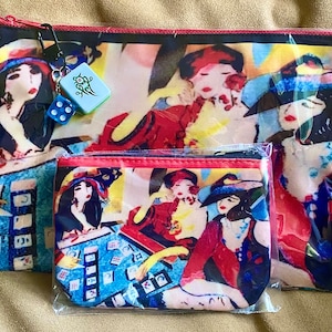 May include: Two red and black zippered pouches with a colorful abstract design featuring women and mahjong tiles. The larger pouch has a blue dice and a green charm with Chinese characters.