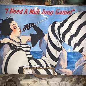May include: A blue and white striped zippered pouch with a black and white illustration of a woman in a striped dress smoking a cigarette. The text "I Need A Mah Jong Game!" is printed on the pouch.